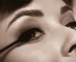 Celebrity gif. An extreme closeup of Audrey Hepburn demonstrating how to apply mascara.