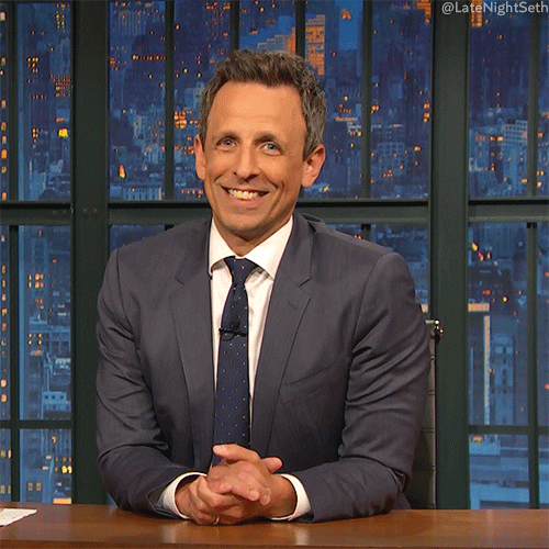 TV gif. Seth Meyers as host of Late Night tilts his head and smiles as he opens his hands in a shrug.