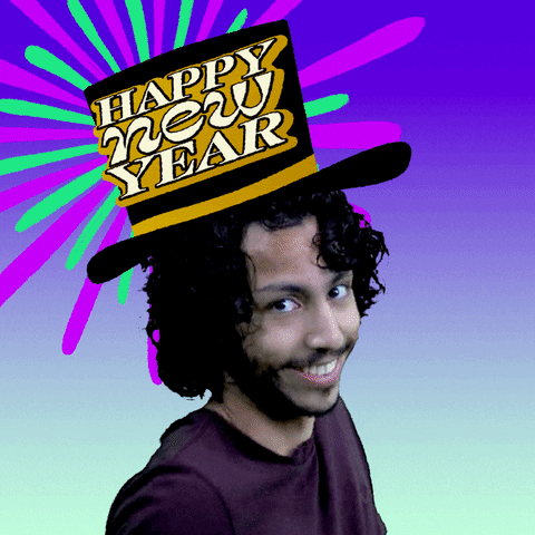 Video gif. Young man with curly hair shimmying his shoulders and wearing a cartoon top hat that reads, "Happy new year," surrounded by an ombre blue background and many big sparkles and fireworks.