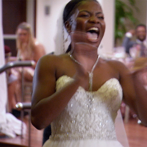 Reality TV gif. Meka from Married at First Sight wears a wedding dress and claps excitedly. 