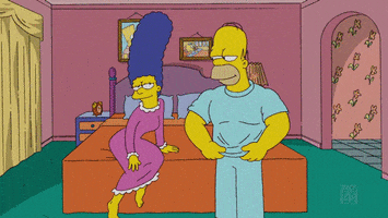 The Simpsons gif. Wearing a nightgown, Marge watches on the edge of the bed in anticipation as Homer removes his shirt, revealing a chiseled chest and abdomen before flexing his biceps in her direction. Marge responds excitedly, curling her toes and bringing her hands to her chest as she says, “Ooohh!”