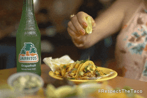 Ad gif. Woman squeezes a lime on top of her plate of tacos, next to a green Jarritos soda bottle. Text at the bottom right reads, "Hashtag Respect The Taco."
