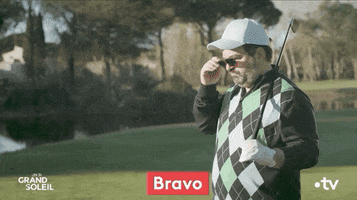 TV gif. A man in an argyle sweater on Un Si Grand Soleil holds a golf club over his shoulder. He takes off his sunglasses as he looks down with raised eyebrows and says, "Bravo."