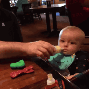 Video gif. Father skillfully squeezes milk out of a baby bottle by continuing to bring it farther away from his baby while the milk still squirts perfectly into the baby's mouth. The baby doesn't even realize just how masterful that was.