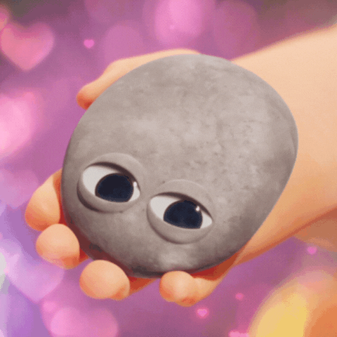 Movie gif. In Minions: Rise of Gru, a child’s hand holds out a pet rock that winks at us.