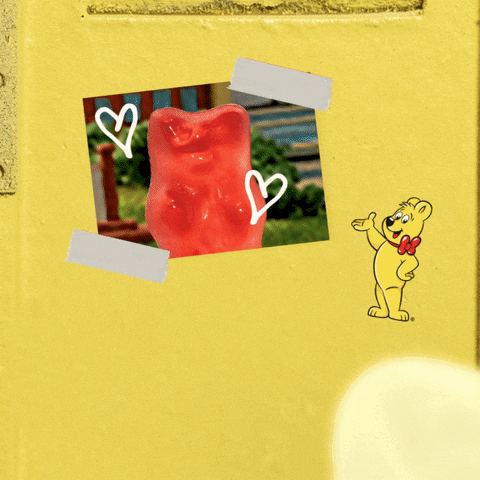 Video gif. A white gummy bear looks at a picture of a red gummy bear they have up in their locker. The white gummy bear shift their weight on both feet and a dialogue box pops out from it, saying, "Miss You."