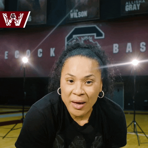 Sports gif. Dawn Staley, head coach of the South Carolina Gamecocks, leans down at us and draws a line at her throat before pursing her lips and walking away.