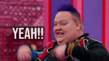 Reality TV gif. A person from Rupaul's Drag Race with short purple hair throws their hands up and shouts with excitement. Text, "Yeah!!"