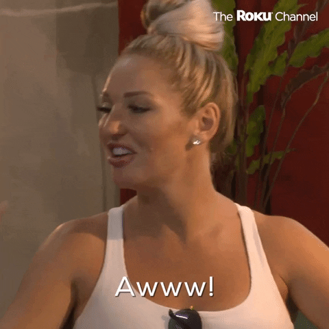 Reality TV gif. Blonde woman looks off and smiles like she's reacting to something totally sweet and adorable. Text, "Aww!'
