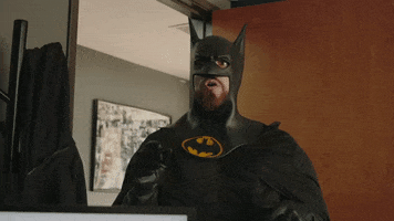 TV gif. Justin Robinson as Batman on Film Riot has a big beard. He raises his hand as if to say, "Yeah that's me."