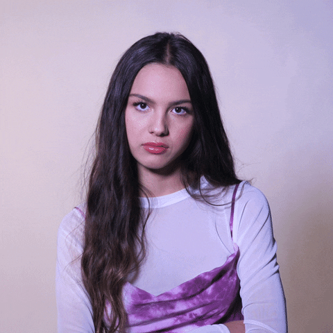 Celebrity gif. Olivia Rodrigo appears annoyed, with arms crossed, shaking her head "no," and rolling her eyes.