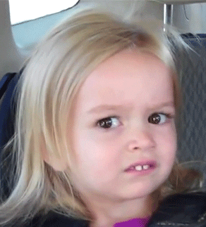 Video gif. Close-up of a little girl in a car seat, looking quizzical and giving a side-eye as her eyes darting back and forth.