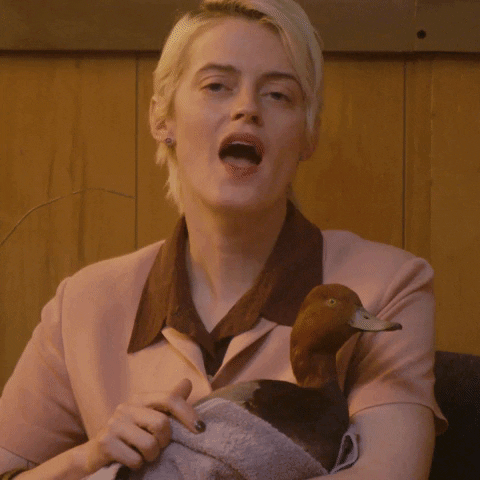 Video gif. Woman holds a duck swaddled in a towel in her arms, mouthing the words "I'm quackers for you" with a proud and dramatic manner, eyelids half closed and adding to the awkward vibe.