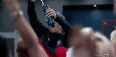TV gif. In a crowd of people cheering, Charlie Hiscock as Will on Ted Lasso pours champagne into a sports drink bottle and shakes his head while exhaling.