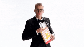 Ad gif. Justin Bieber in a T-Mobile Super Bowl 51 advertisement points off-screen while holding a popcorn bag in his other hand.