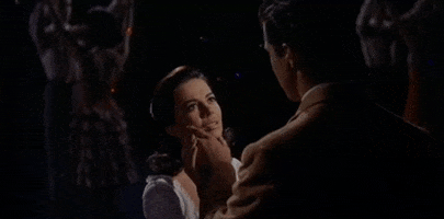Movie gif. Natalie Wood as Maria and Richard Beymer as Tony. Tony gently strokes Maria's jawline as they look deep into each other's eyes and hold hands. Tony says, "So beautiful."