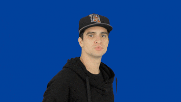 Celebrity gif. Brendon Urie stands in front of a solid blue backdrop and flicks his head back sassily while chewing his gum with attitude. He confidently walks away while staring straight at us.
