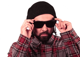 Video gif. Man lowers his sunglasses to show himself rolling his eyes.