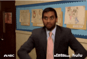 Parks and Recreation gif. Aziz Ansari as Tom looks at someone off screen and throws a bunch of dollar bills into the air. 