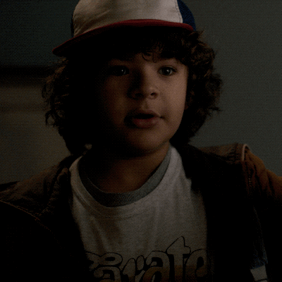 TV gif. Gaten Matarazzo as Dustin on Stranger Things looks up at someone with a wide sweet smile, squirting his eyes as his smile spreads across his face.