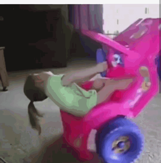 Video gif. A little girl with a ponytail and a binky in her mouth sits in a pink ride-on toy jeep. The car slowly spins in circles on its back wheels. The little girl leans back in the car with not a care in the world and her ponytail just dangling in the air. 