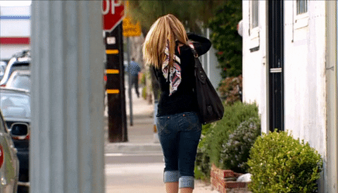 Reality TV gif. Lauren Conrad walks down a street, back turned to us. She slips her hair over her shoulder and does a little run in short bursts as if trying to get away a little quicker.
