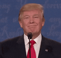 Political gif. A smug Donald Trump stands in front of a microphone, lifting his chin and nodding slightly.