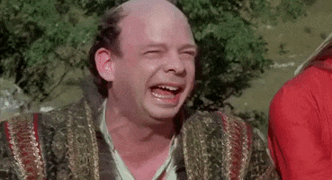 Movie gif. Wallace Shawn as Vizzini in The Princess Bride laughs with a big smile on his face. He abruptly stops laughing and pauses with a big open smile, falling over to his side like a brick.