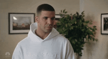SNL gif. Drake shifts his gaze around before pursing his lips and biting his tongue.