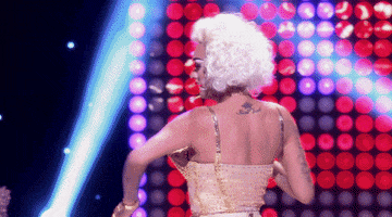 Reality TV gif. Sutan Amrull is performing on RuPaul's Drag Race and they put a monocle up to their face as they laugh.