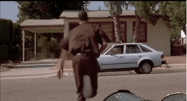 Movie gif. DJ Pooh as Red from Friday wearing a delivery uniform runs sloppily across the street toward a parked car, his arms flailing about as he runs.