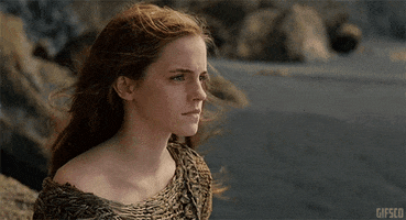 Movie gif. Standing on the beach as the wind blows her hair, Emma Watson, as Ila in Noah gives a forlorn look over her shoulder.