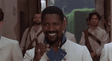 Movie gif. Denzel Washington as Don Pedro in Much Ado About Nothing bites his lip as he points ahead with a smile. 