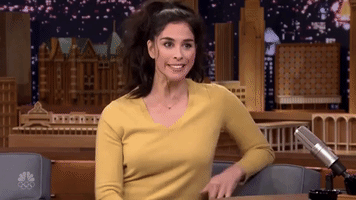 Tonight Show gif. Sarah Silverman raises her hands and shrugs awkwardly as she glances around as if confused. Text, "I don't know?"