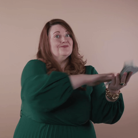 Reaction gif. A non-apparently Disabled white woman with with anxiety and depression and long red hair slides palm over palm, making it rain, before she runs out of cash.