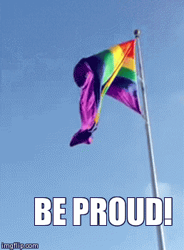 Digital art gif. A rainbow flag on a vertical flagpole, flapping slowly in the breeze. Text, "Be proud!"
