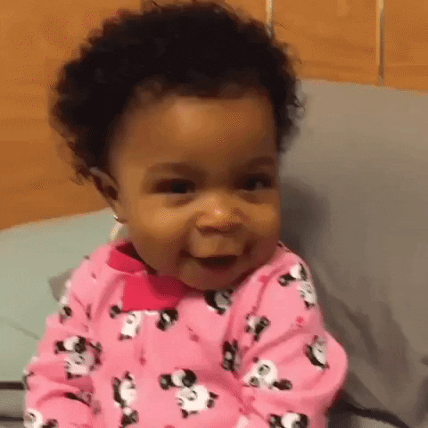 Video gif. An adorable toddler girl wearing pink pajamas with pandas alternates several times between frowning dramatically, then slowly smiling delightedly.
