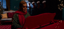 Celebrity gif. Elton John is playing the piano and singing as it slowly brings him on the stage. Everything is green and red and he's performing for a Christmas event.