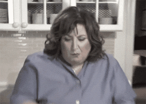 woman picking out food that's stuck in her teeth GIF