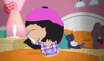 Cartoon gif. Wendy Testaburger from South Park wears pink beret and purple flannel pajamas as she twirls around with her smartphone on her bed, squeezing her eyes shut like she couldn't be any happier in this moment.