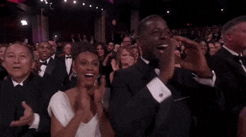 Oscars 2024 GIF. Sterling K Brown and Ryan Michelle Bathe, applaud and cheer with joy, Sterling cupping his hands and hollering.