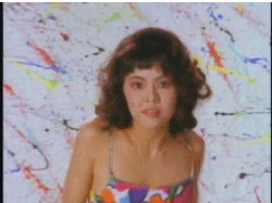 An animated gif of a young woman looking into the camera and bopping, rolling her shoulders in a dance