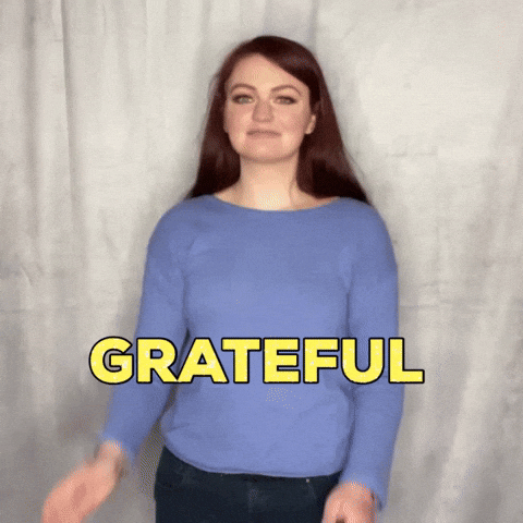 Video gif. A woman stands in front of a backdrop and puts her hands in prayer hands before looking at us knowingly, saying "Grateful."