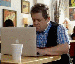 Celebrity gif. Patton Oswalt is on his laptop in a cafe and something goes terribly wrong. He freaks out and throws a mini tantrum, gesturing at the screen and looking around to rant at someone, anyone.