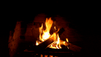 Video gif. Cozy fire burns in a brick fireplace.