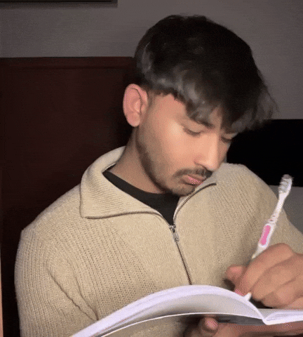 Person sitting at a desk writing notes in an open notebook with a pen