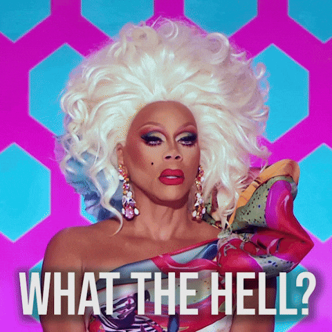 Reality TV gif. RuPaul in RuPaul's Drag Race wears a voluminous blonde wig and colorful one-shoulder top with a puffy sleeve. Text, "What the hell?"
