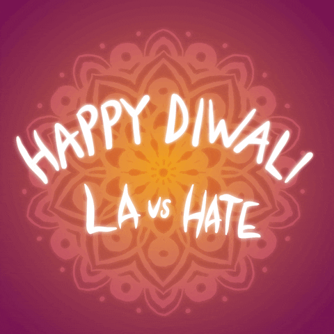 Digital art gif. Misty mandala glowing sunrise orange on a sangria red background. Text, "Happy Diwali, Love light and happiness. LA vs hate."