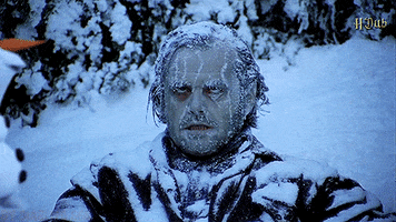 Movie gif. Jack Nicholson as Jack Torrance in The Shining is frozen over from the bitter cold, as snow piles up on his clothes and coats his hair. His angry eyes are rolled back, but the energy is uplifted by a happy Olaf strolling through and grinning at us.