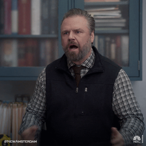 TV gif. Tyler Labine as Dr. Iggy on New Amsterdam. He squints his eyes in thought and crosses his arm as he leans against a desk, contemplating the news he's received.